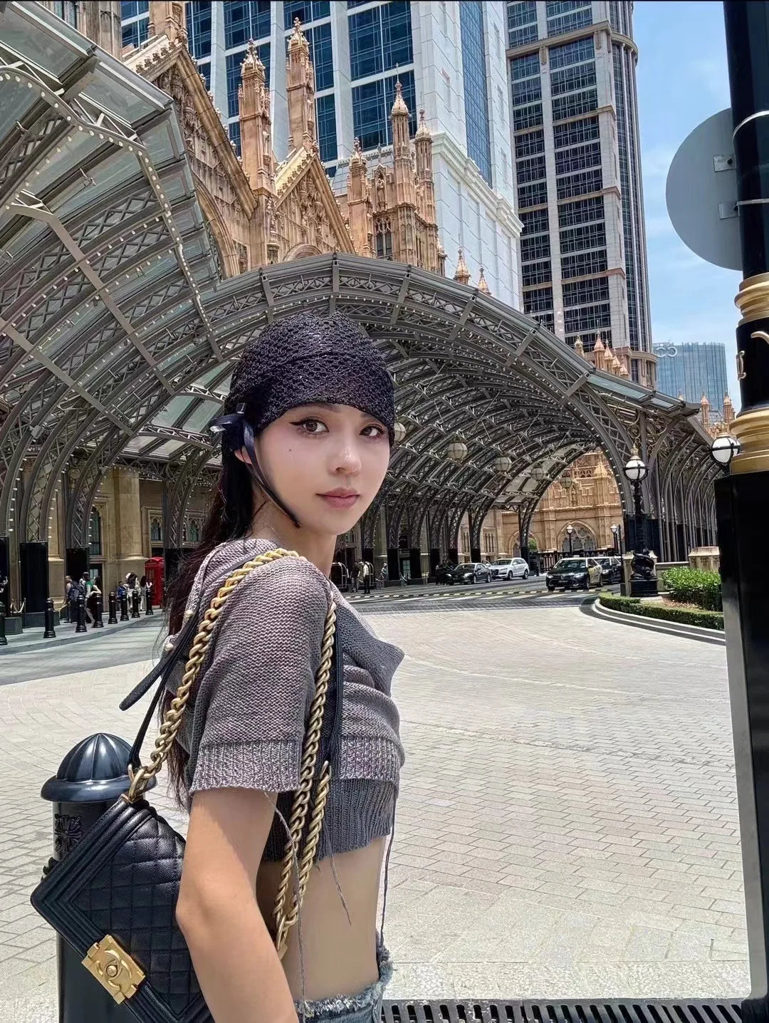 A young woman wearing a chic, black open-knit beanie with a delicate side bow detail.