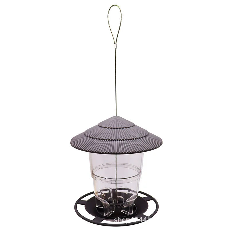 Clear plastic bird feeder with a grey, ribbed, pagoda-style roof and a circular black base, hanging from a wire loop.