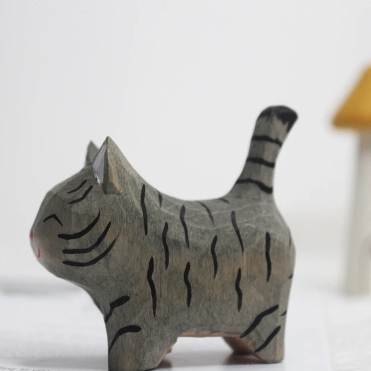 Hand-carved grey wooden cat figurine with black tiger-style stripes, pointed ears, and a raised tail.