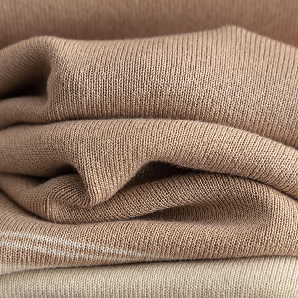 Close-up of soft, folded light-brown knit fabric with a fine-gauge texture and subtle stripe detail.