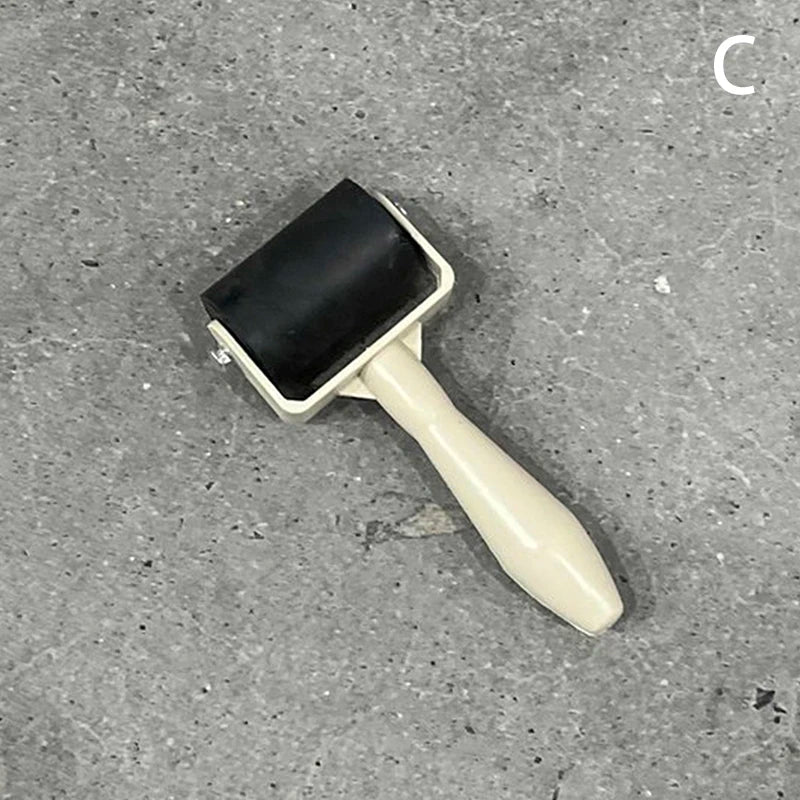 Black rubber craft roller with a cream-coloured handle on a grey background.