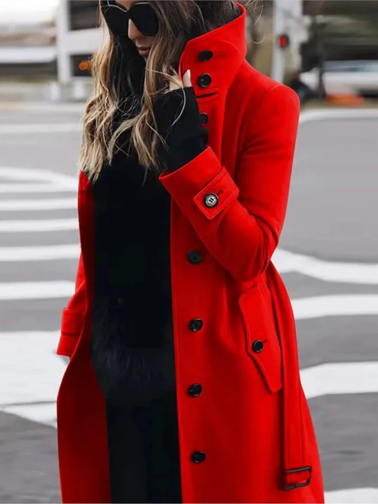 A woman wears a vibrant red, knee-length tailored coat with a high collar, black buttons, and button-tab cuffs.