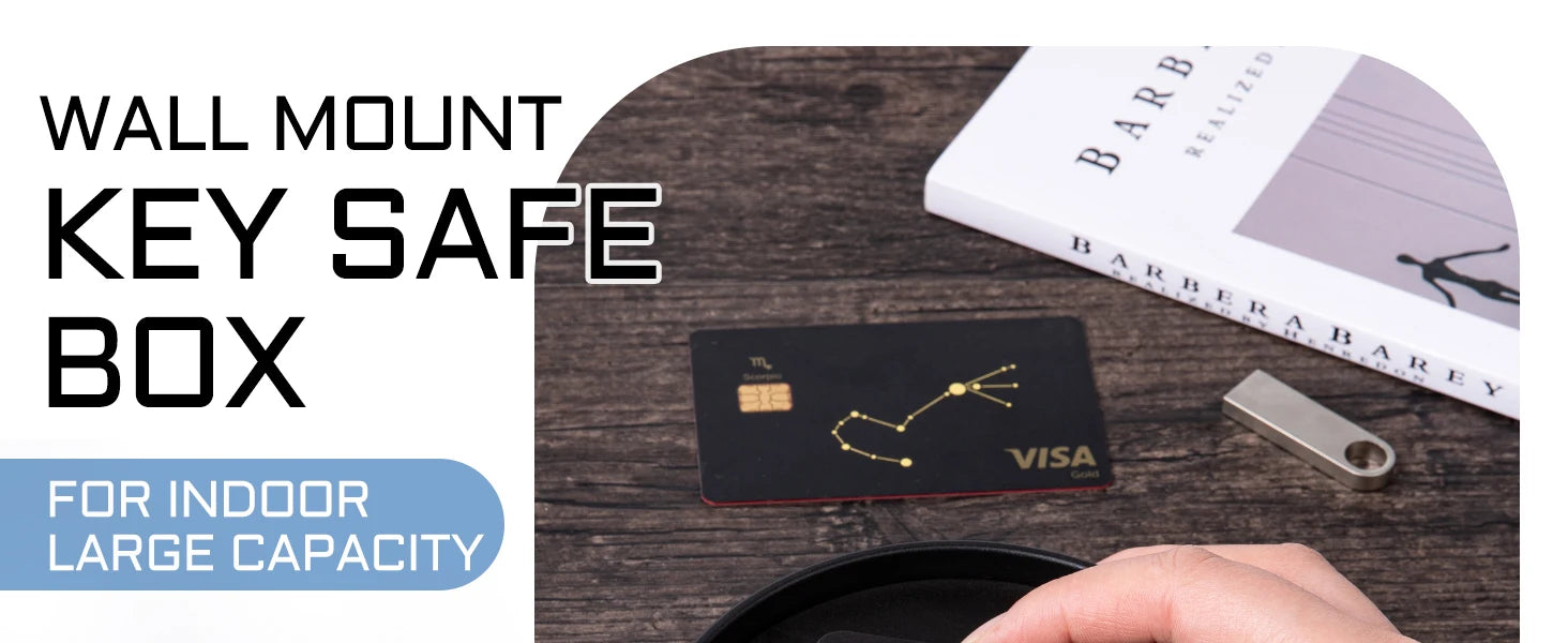 A black metal wall-mount key safe box shown on a wooden desk next to a credit card and a small metallic key fob.