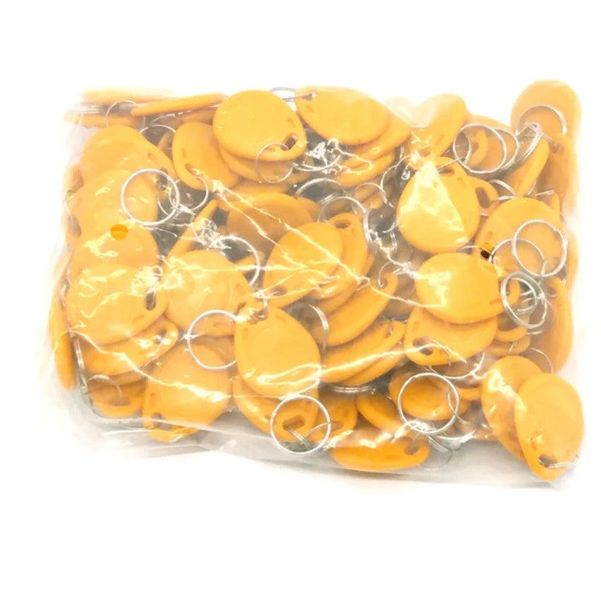 Bulk bag of yellow plastic RFID key fob tags with metal rings.