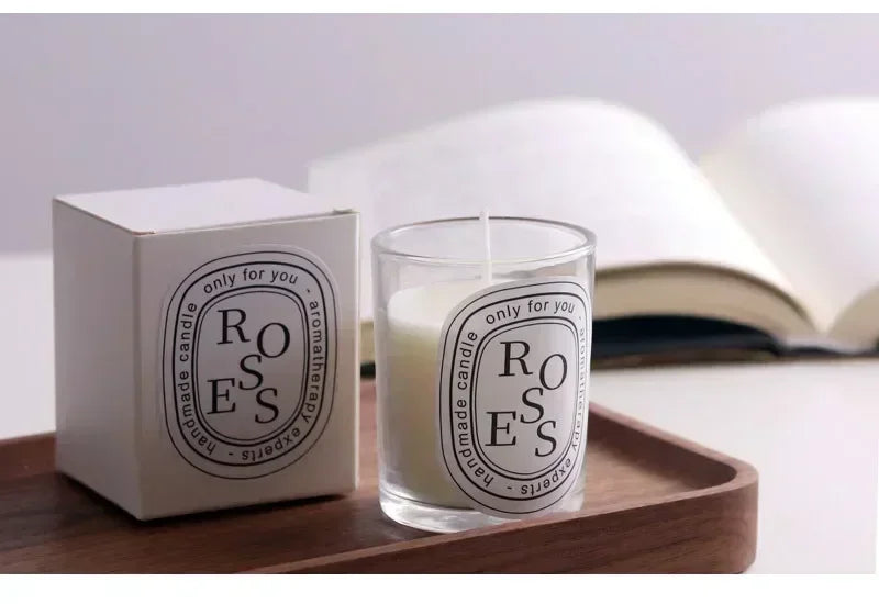 White scented candle in a glass jar with matching gift box on a wooden tray, featuring elegant black typography.