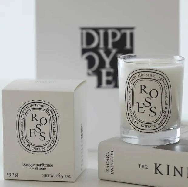 Scented candle in a clear glass jar with a white label, standing next to its matching cream-coloured gift box.