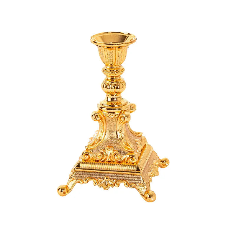 Gold metal candlestick holder with ornate floral scrollwork and a wide square base on four feet.