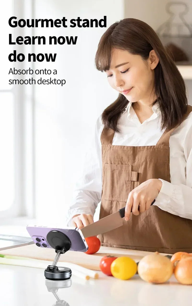 A black, adjustable magnetic phone stand mounted on a kitchen counter holding a smartphone upright for a home cook.