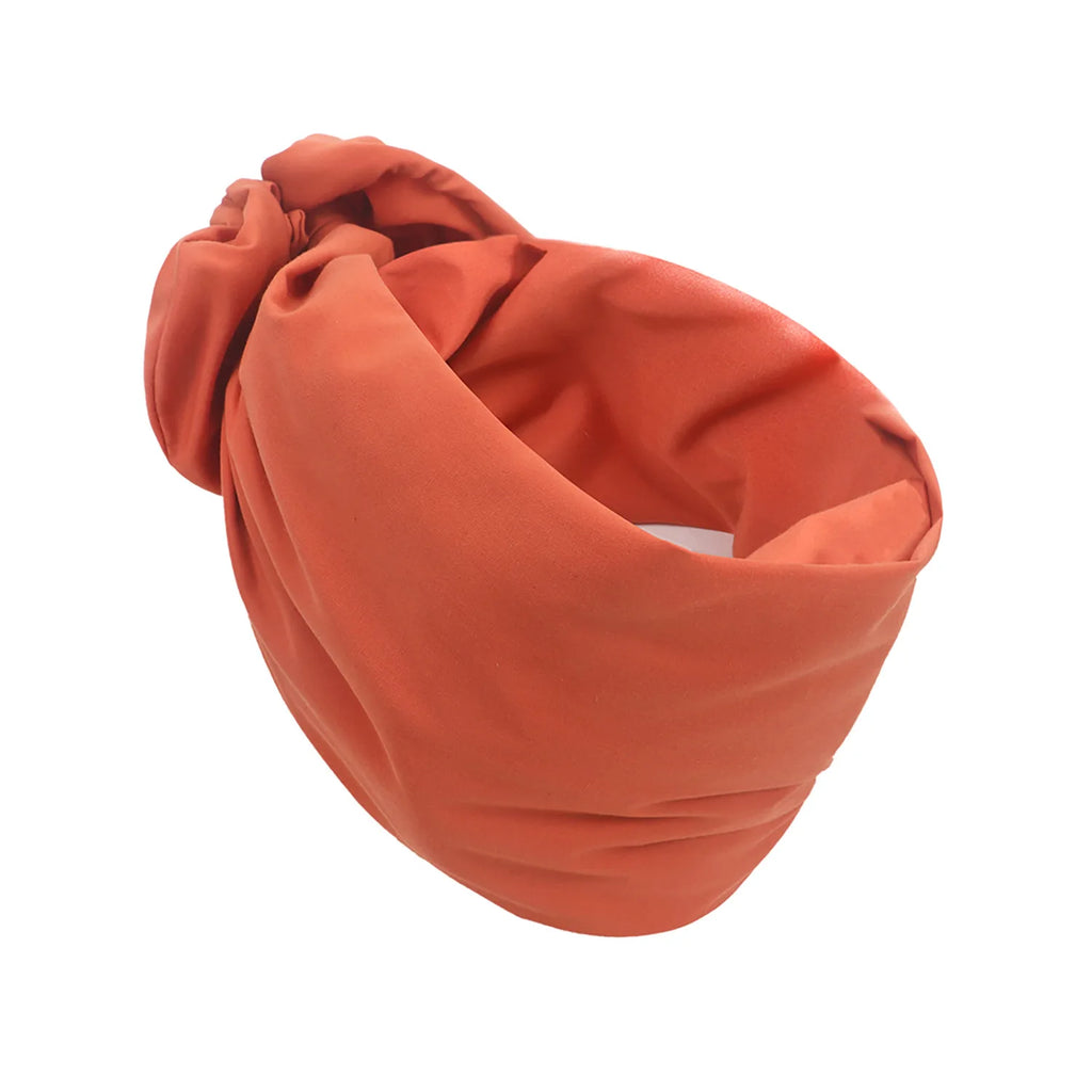 Burnt orange vintage-style turban hat with a soft, knotted front detail and comfortable draped fabric design.