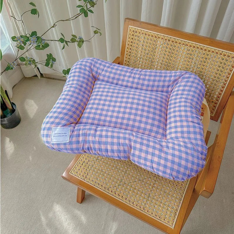Purple and pink plaid pet bed with raised bolsters and a rectangular flat cushion, resting on a wooden chair.
