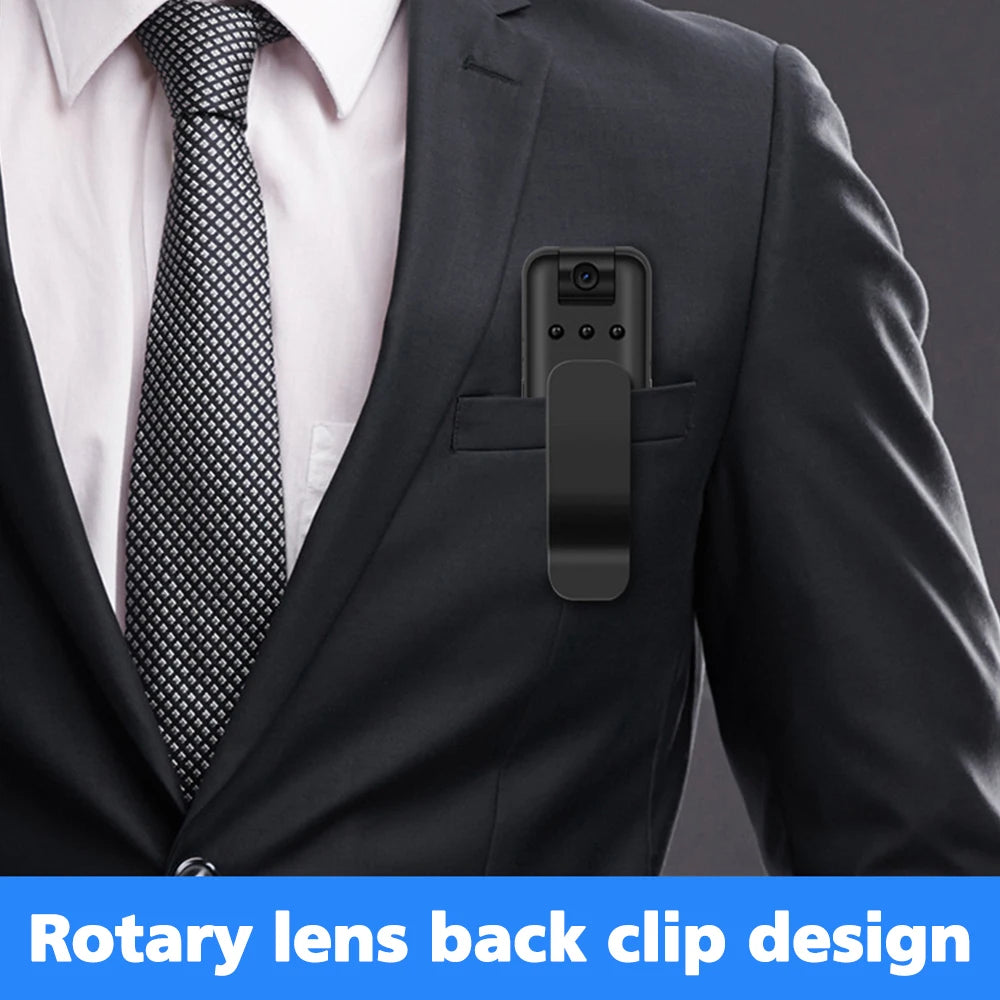 Black plastic body camera with a rotating lens and a belt clip, clipped into a suit jacket breast pocket.