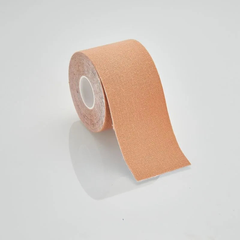 A single roll of beige kinesiology sports tape, partially unrolled, against a white reflective background.