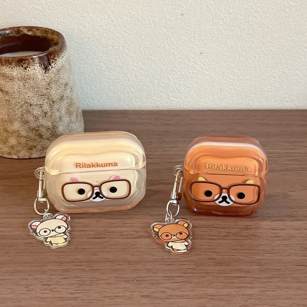 Two Rilakkuma-themed clear plastic AirPods Pro cases in cream and brown with matching character charms.