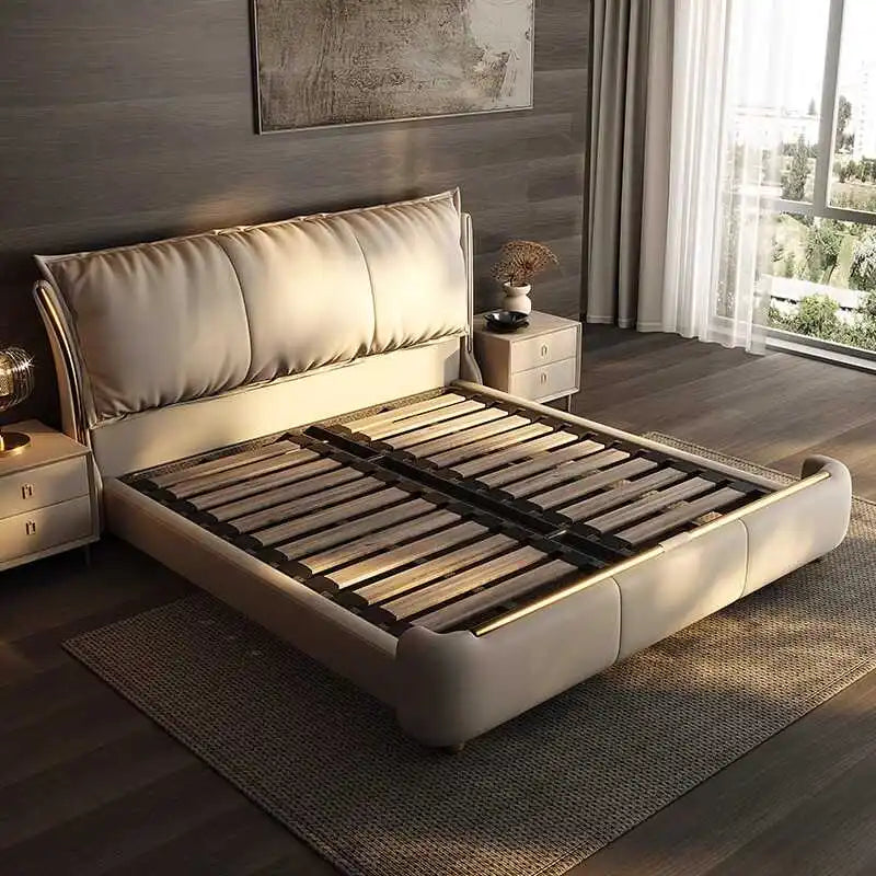 Modern beige double bed frame with a large, plush cushioned headboard and sleek gold trim accents on a wooden base.