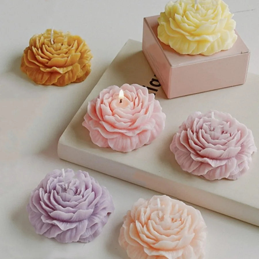Assorted pastel-coloured, peony-shaped decorative candles in shades of pink, yellow, purple, and cream.