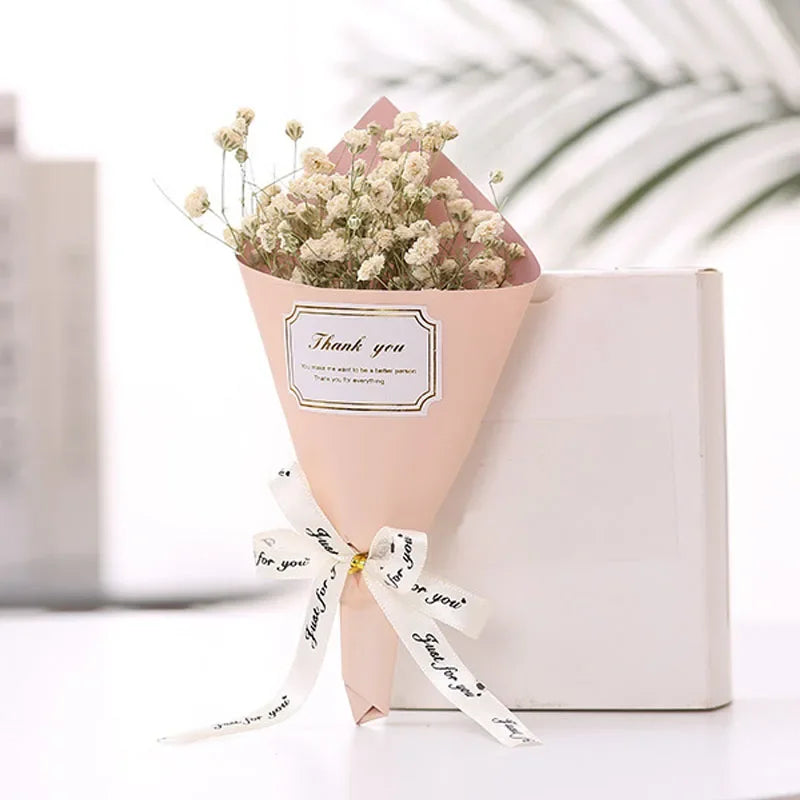 A small bouquet of dried white flowers wrapped in pink paper, tied with a 'Just for you' white ribbon.