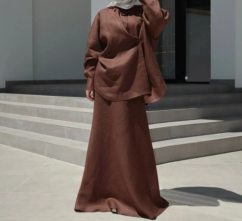 Brown linen two-piece set featuring a loose, long-sleeved button-up top and a matching floor-length maxi skirt.