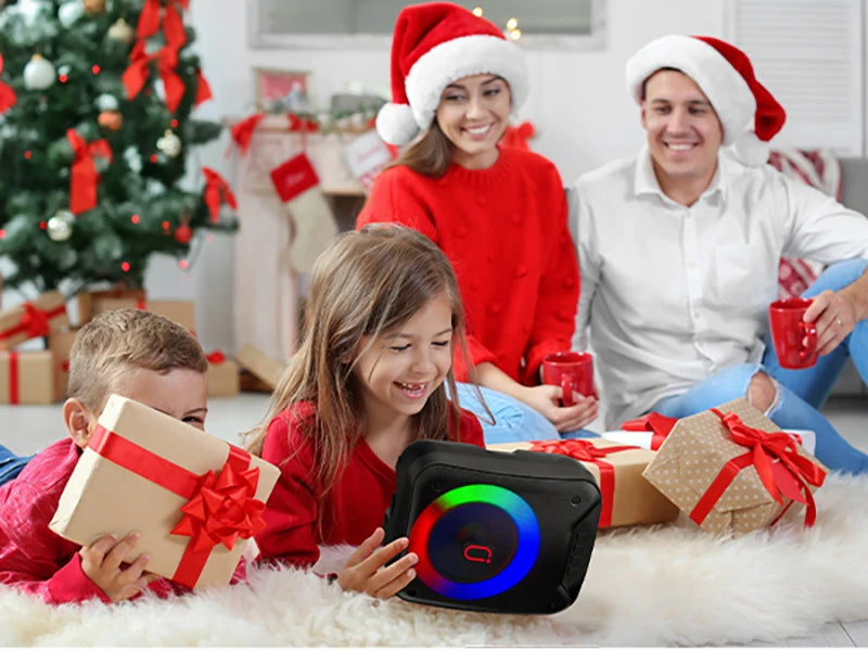 Black portable wireless speaker with vibrant LED ring light, held by a family in a festive Christmas setting.