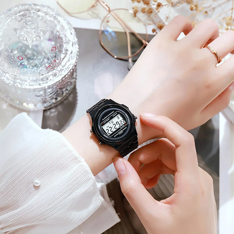 A sleek black retro-style digital LED watch with a metallic bracelet strap worn on a woman's wrist.