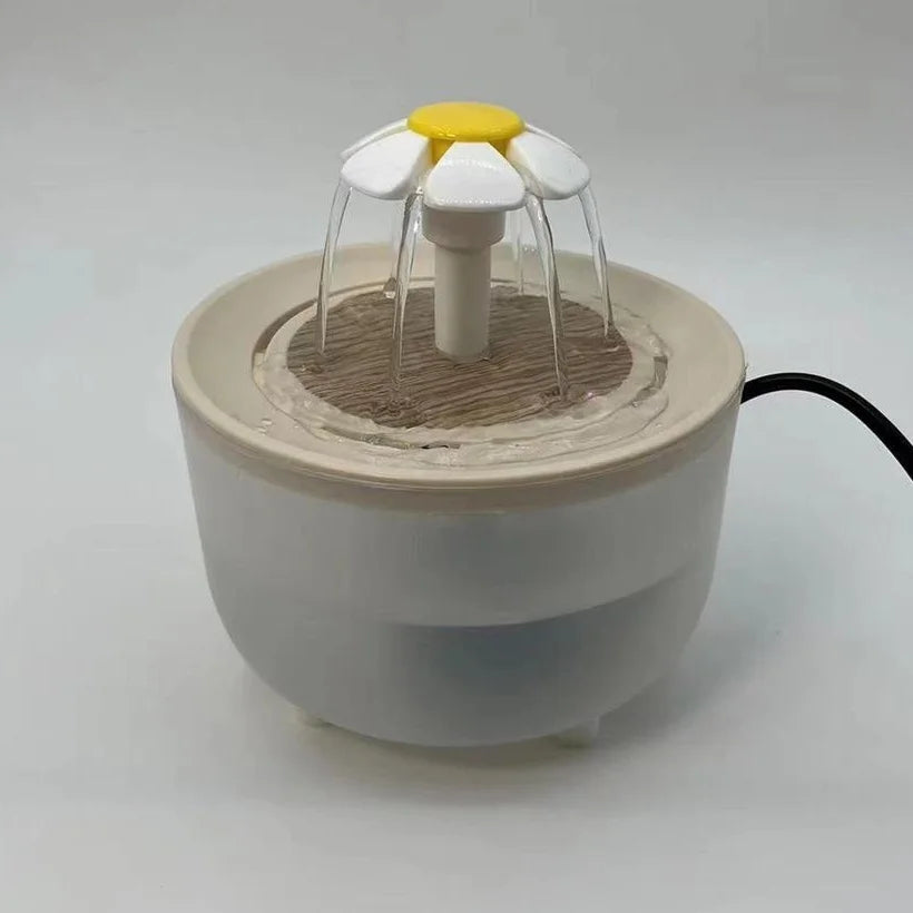 White pet water fountain with a daisy-shaped flower topper, wood-look base, and clear plastic bowl.