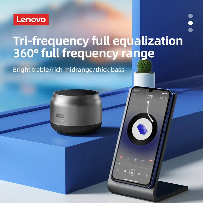 A sleek, metallic silver portable wireless speaker next to a smartphone in a stand, displaying music playback controls.