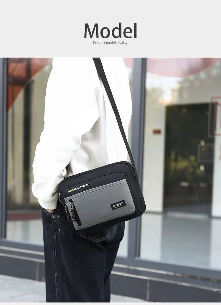 A man wearing a black and grey rectangular crossbody shoulder bag with a zipped front pocket and adjustable strap.