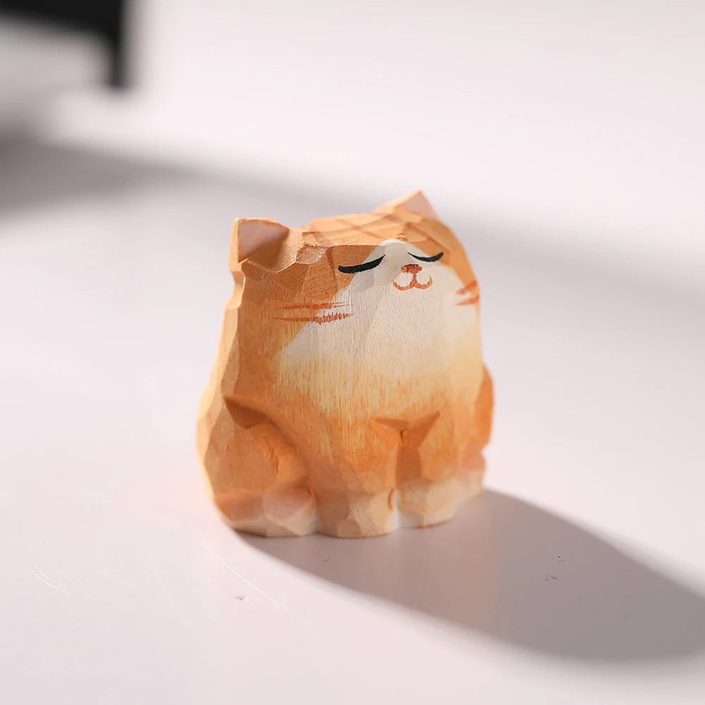 Small, hand-carved wooden orange cat figurine with a peaceful, sleeping expression and faceted geometric style.