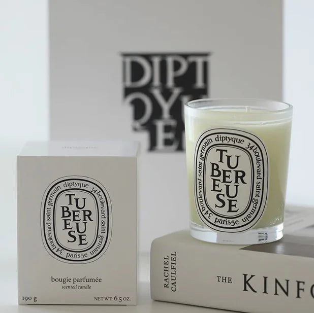 Luxury scented candle in a clear glass jar with a white label, displayed next to its matching white packaging box.