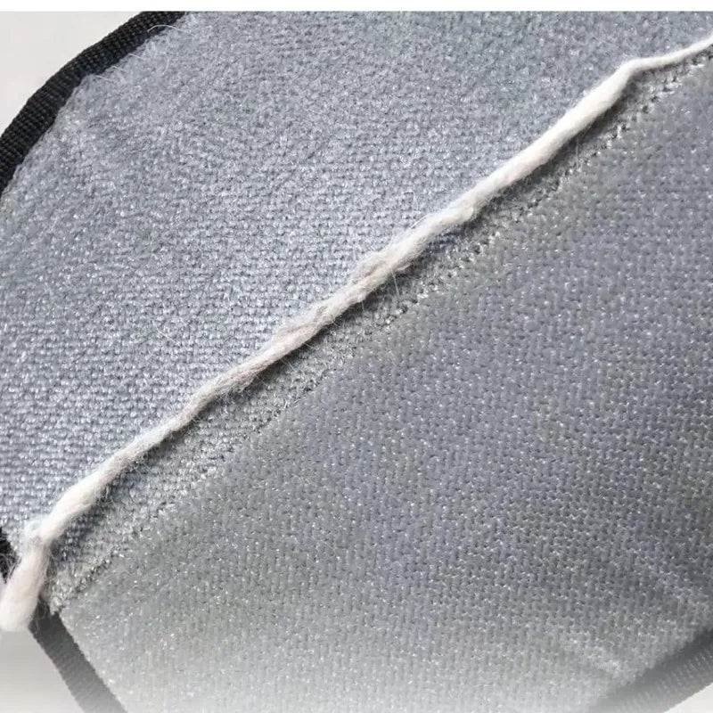Close-up of a textured, grey hook-and-loop fabric fastener with a loose white thread running across the surface.
