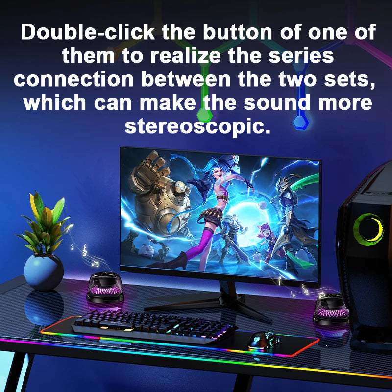 Two black portable mini speakers with glowing purple bases set up on a gaming desk with a computer monitor.