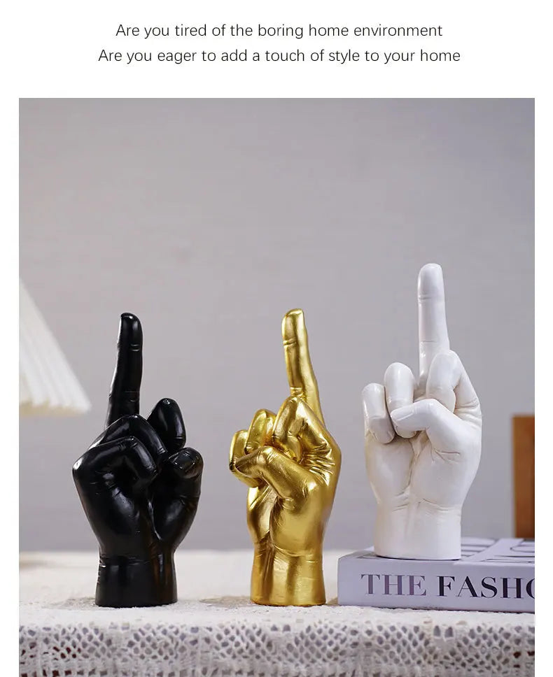 Three hand-shaped decorative ornaments in black, gold, and white, each showing a middle-finger gesture.