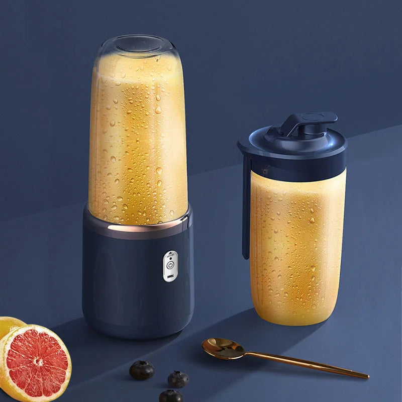 Portable dark blue personal blender with a transparent cup filled with orange smoothie, plus a matching travel lid.