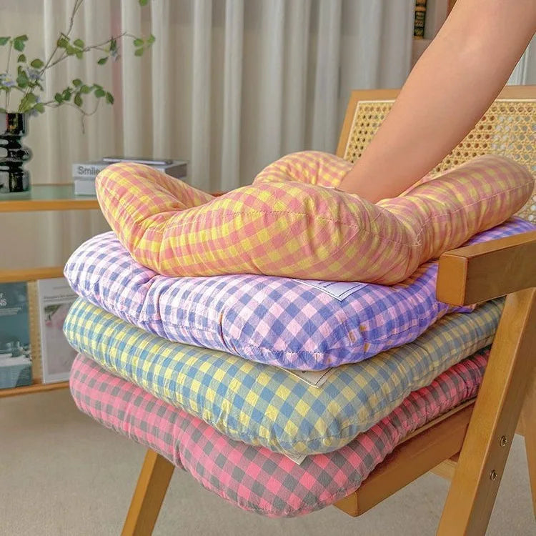 Stack of four soft pet mats in pink, purple, blue, and yellow gingham patterns on a wooden chair.