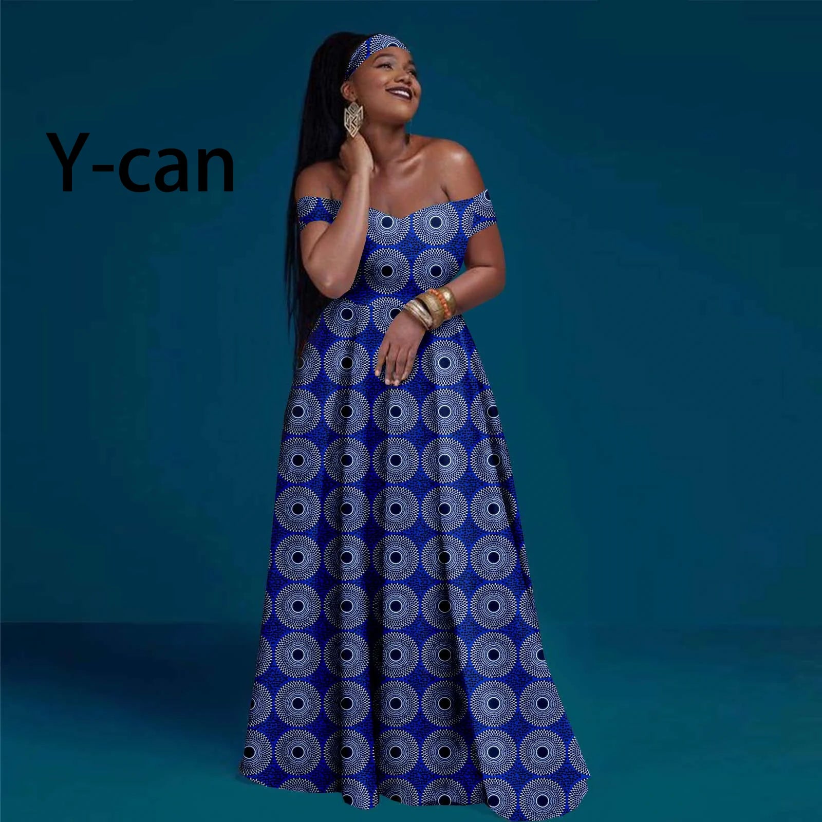 Model wearing a blue and white off-shoulder maxi dress with a circular geometric print and matching headwrap.
