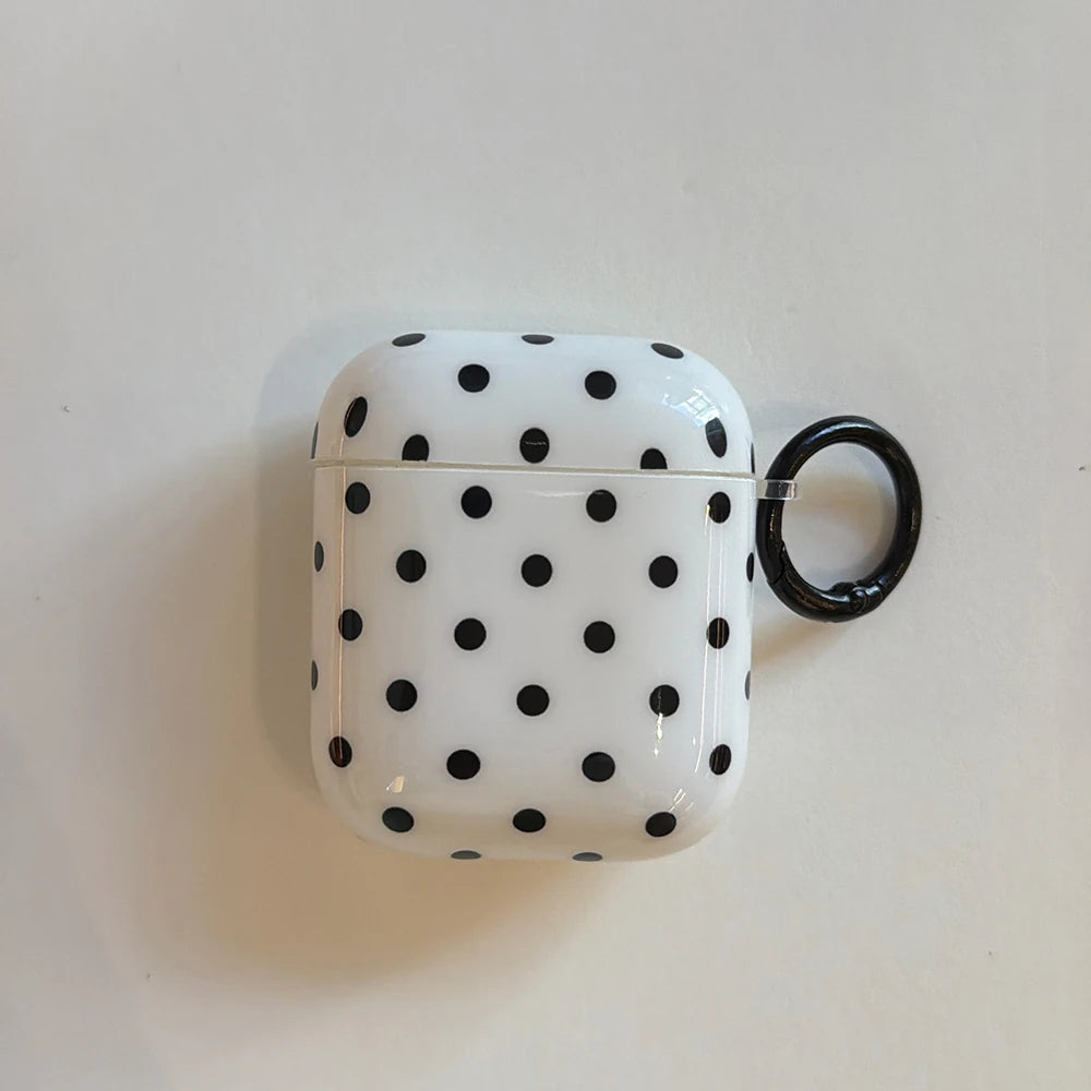 White and black polka dot hard plastic AirPods case with a black carabiner ring. Compatible with AirPods 1 & 2.