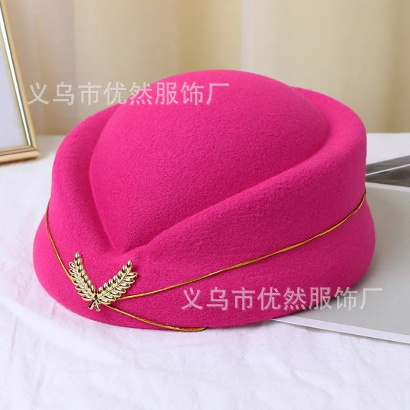 Bright pink vintage-style pillbox stewardess hat, featuring a gold trim and gold leaf detail.