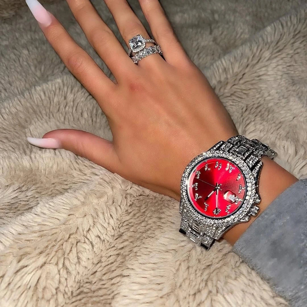 Women's watch with a vibrant red dial and crystal-encrusted silver-tone strap and bezel on a wrist.
