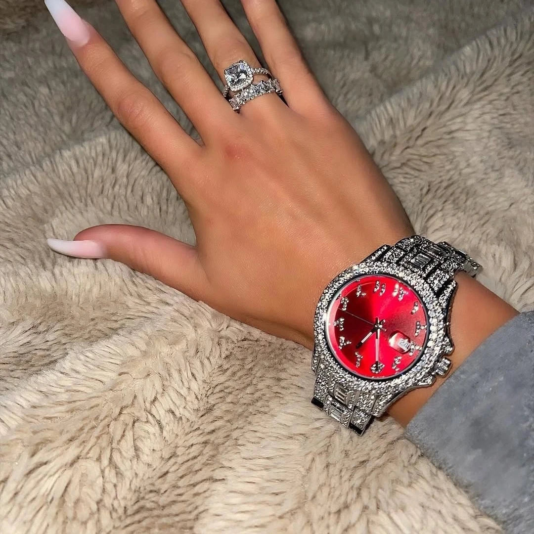 Women's watch with a vibrant red dial and crystal-encrusted silver-tone strap and bezel on a wrist.