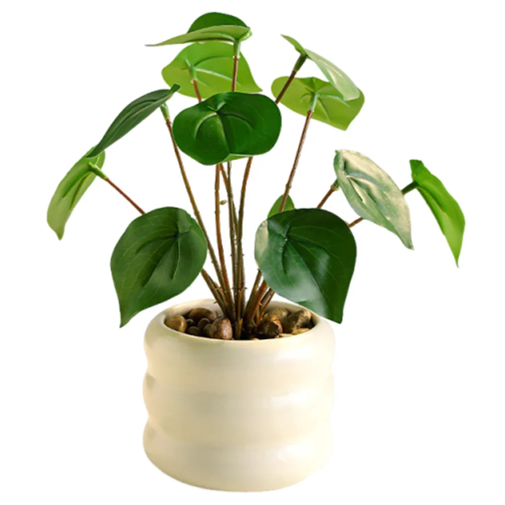 Artificial tropical plant with vibrant green leaves in a cream-colored, ridged ceramic pot filled with small pebbles.