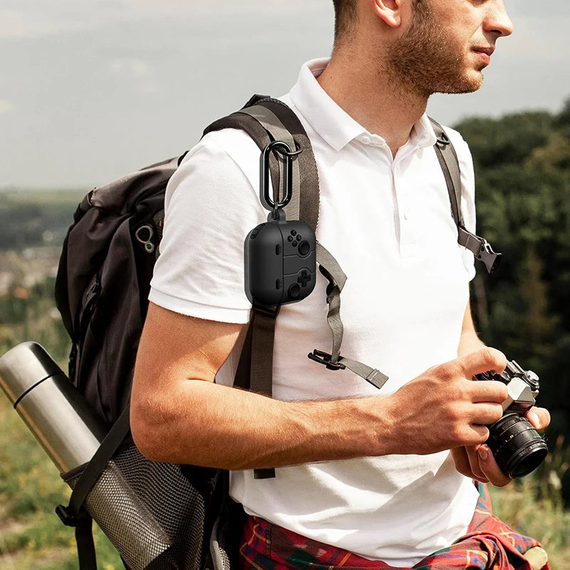 Black silicone gaming controller-style case for AirPods Pro, attached to a backpack with a carabiner.