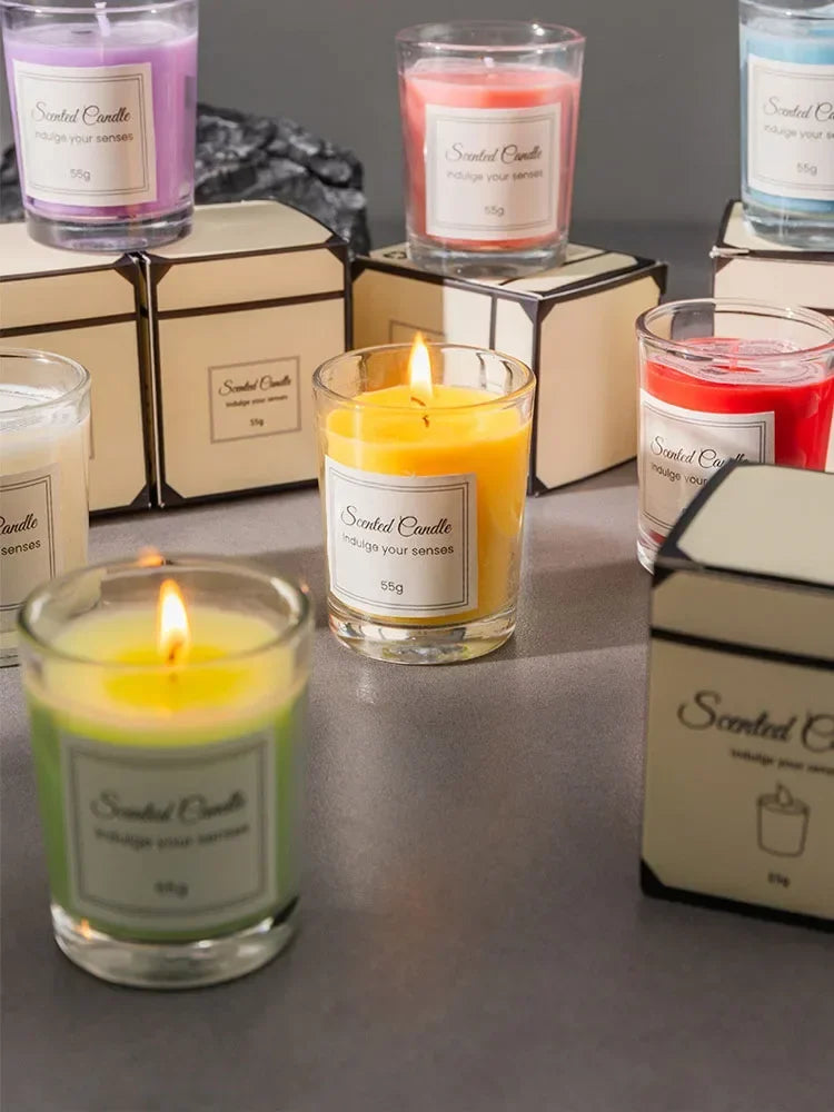 Assorted colourful 55g scented candles in glass jars, each with a minimalist label and matching individual gift box.