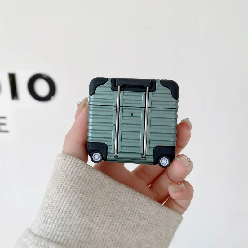 Sage green, luggage-style hard shell AirPods case with handle and wheel detailing.