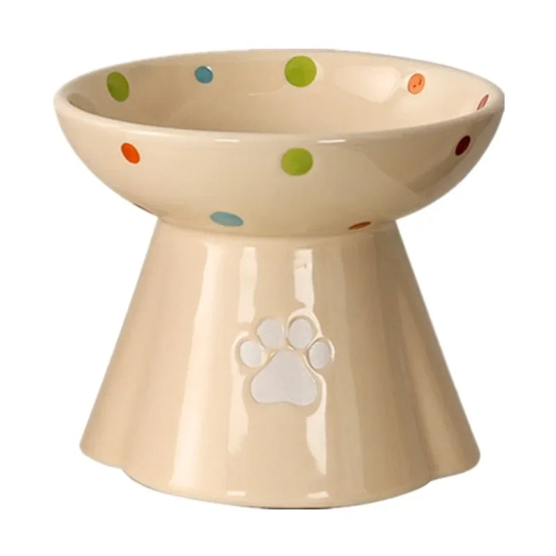 Cream-coloured ceramic elevated cat bowl with colourful polka dots and a paw print cutout on the base.