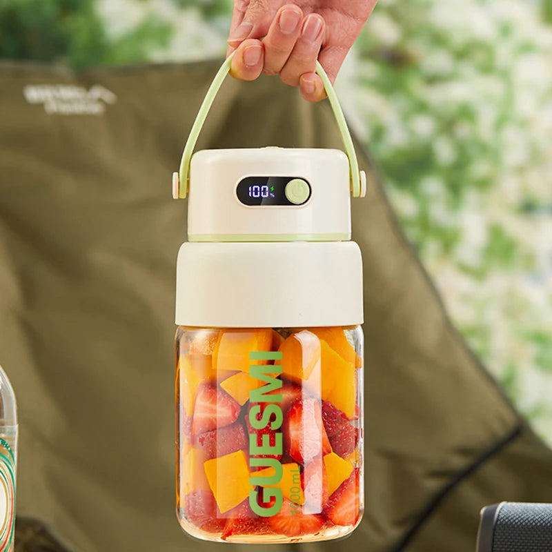 Portable cream-colored electric blender with a digital display, light green handle, and filled with fruit pieces.