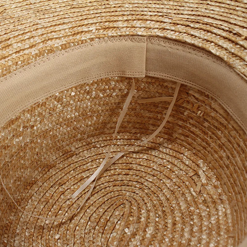 Interior view of a natural straw sun hat showing the woven texture and an internal elasticated sweatband.