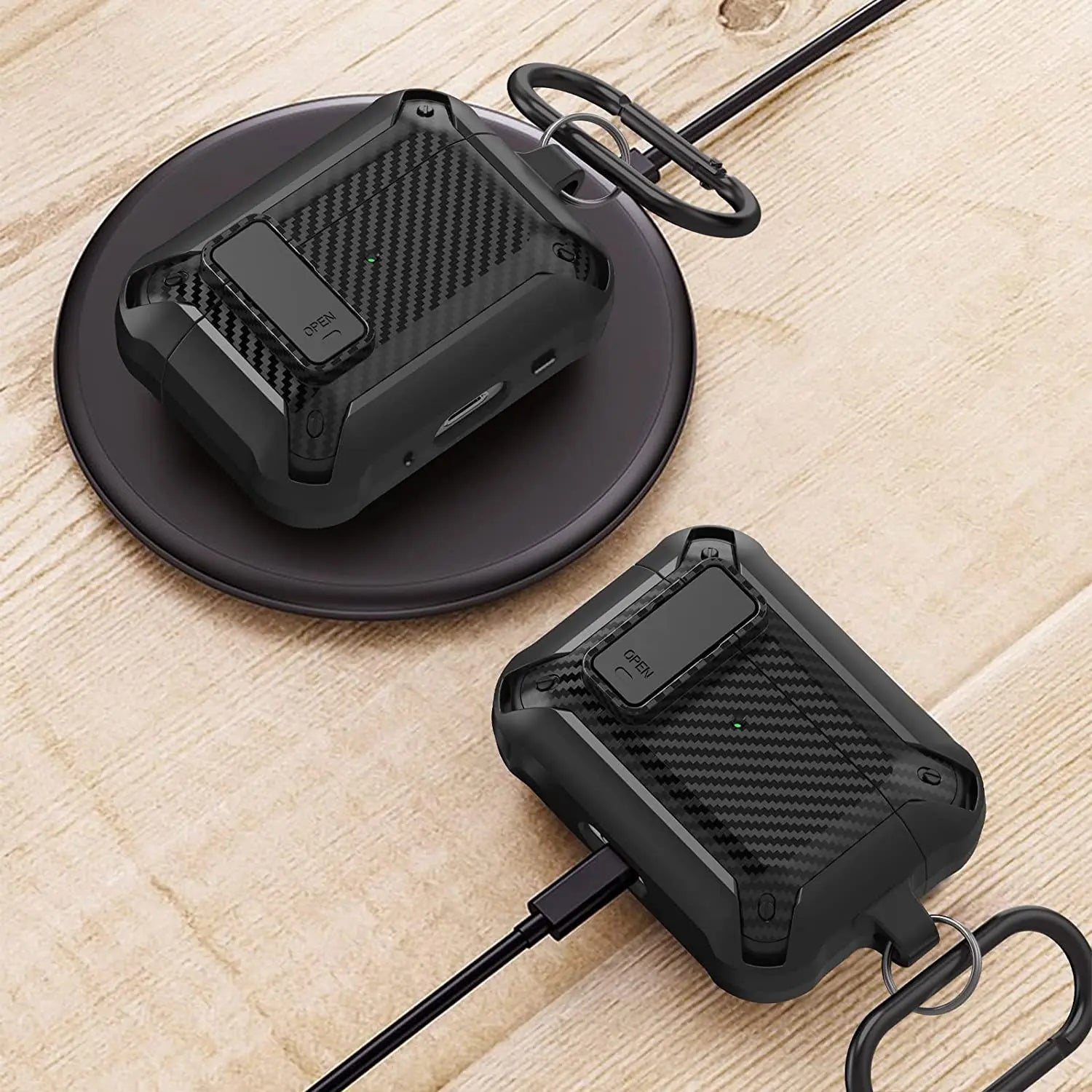 Rugged black carbon fibre-style protective case for AirPods with locking latch and carabiner, on charging pads.