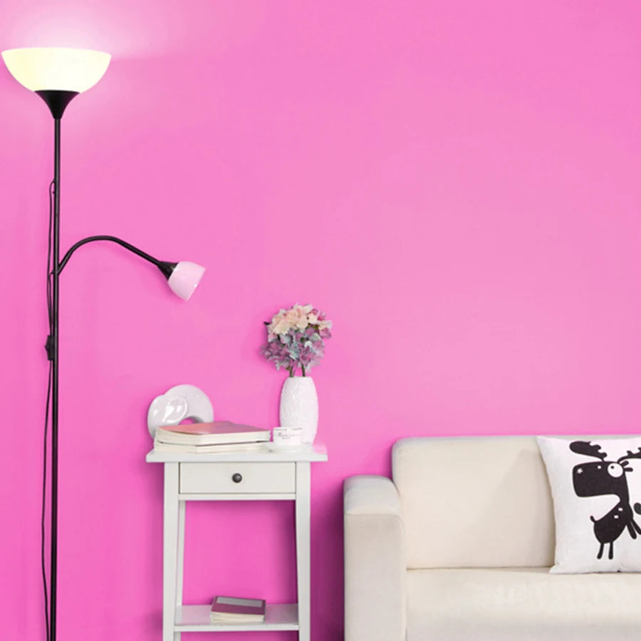 Bright pink matte self-adhesive wallpaper applied to a living room wall behind a white sofa and side table.