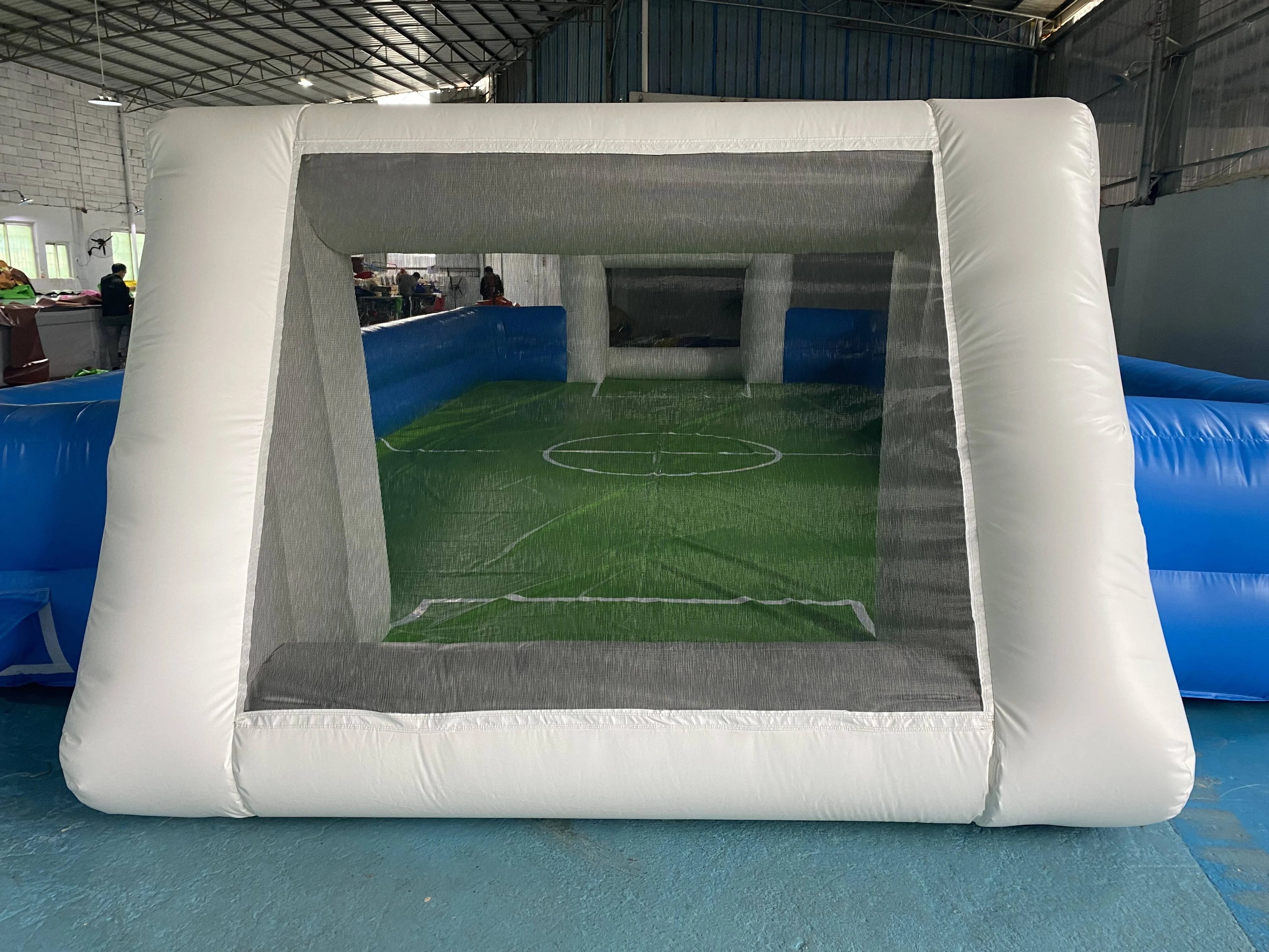 Inflatable football pitch with white goal frame, blue side walls, and a printed green pitch floor.