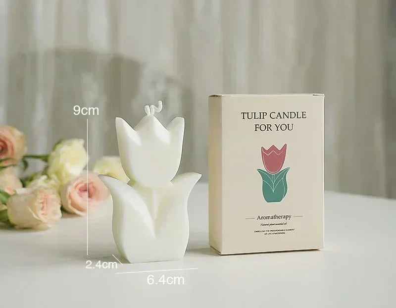 A white, tulip-shaped aromatherapy candle next to its matching cream-coloured gift box on a white surface.