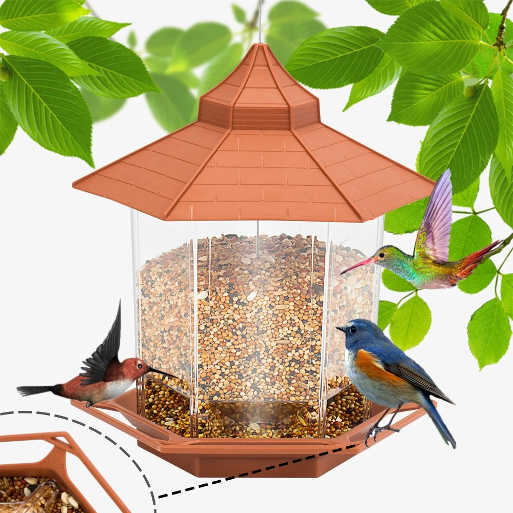 Hexagonal hanging bird feeder with a brown roof and clear plastic sides, filled with seeds, surrounded by birds.